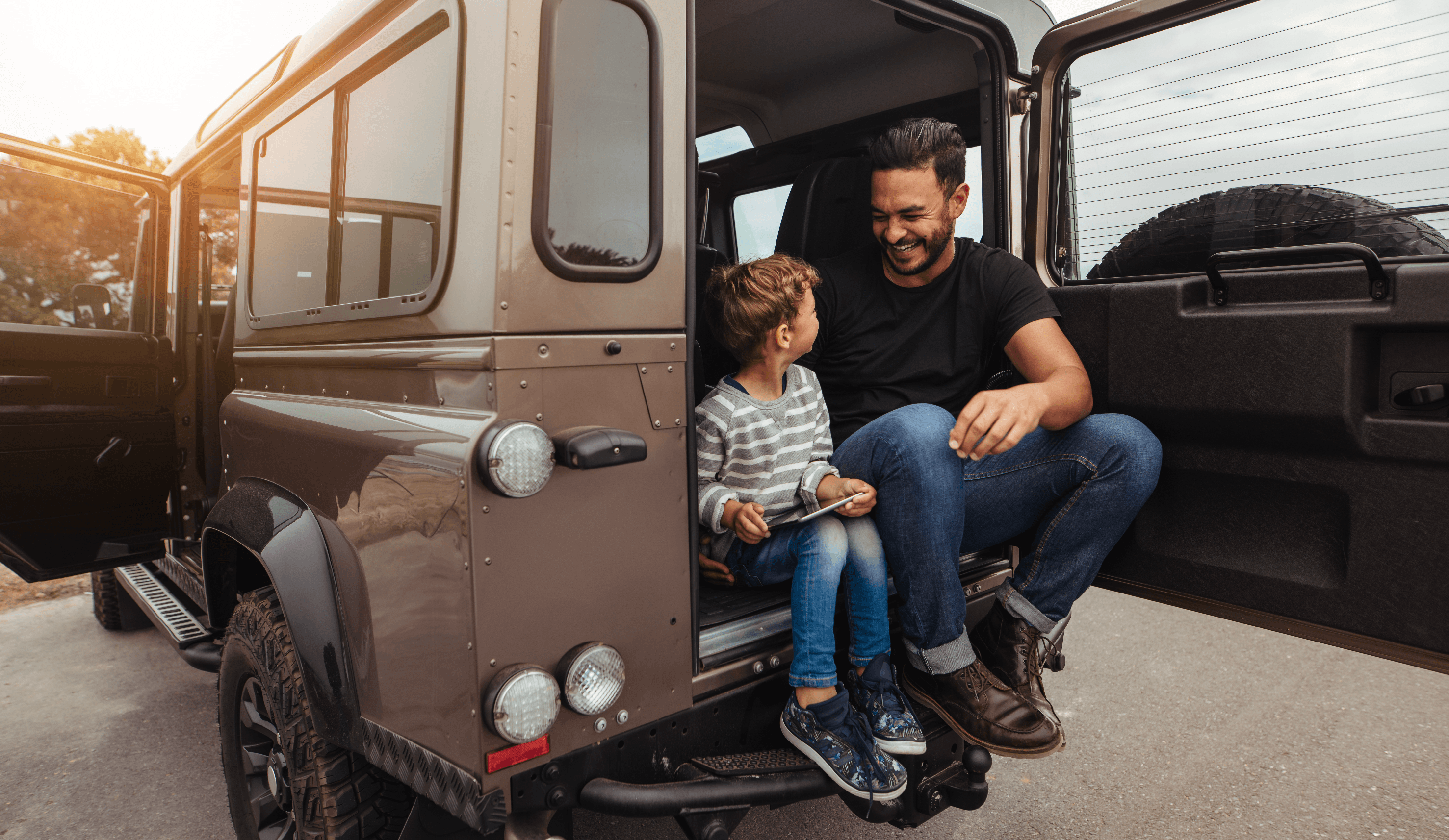 Hombre con su hijo en parte de atrás de un coche.